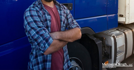 truck driver standing next to blue truck with arms crossed